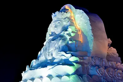 Illuminated ice sculpture of a seated figure with ornate details at night in Harbin Ice and Snow World, Harbin, China.