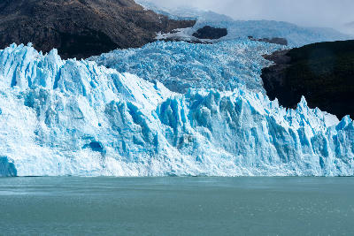 Close view of Upsala Glacier ice wall with blue crevasses and glacial lake in Patagonia, Argentina.
