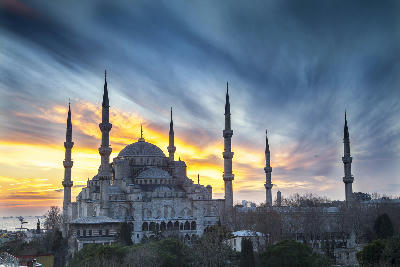 Blue Mosque in Istanbul silhouetted against a colourful sunset sky.