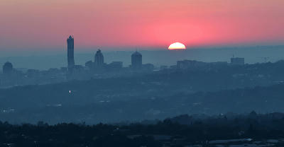 Sunrise behind the Sandton skyline in Johannesburg, with commercial towers emerging through winter morning haze.