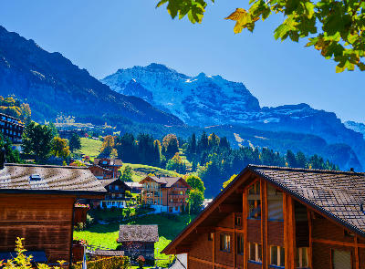 Wengen chalets on a hillside with alpine meadows and snow-capped mountains rising in the background, Switzerland.