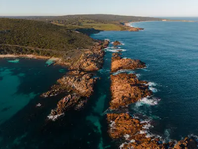 Aerial view of Canal Rocks showing long granite formations, turquoise ocean channels and the rugged Margaret River coastline in Western Australia.