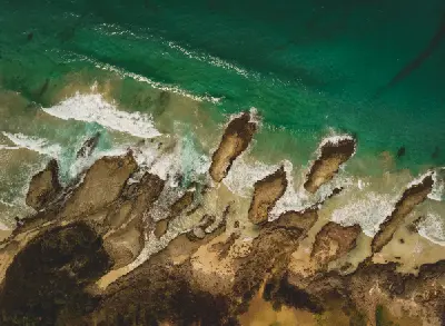 Top-down aerial view of waves breaking around the offshore rock formations and rugged shoreline at Cathedral Rocks near Kiama.