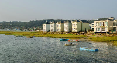 Waterfront houses overlooking Knysna Lagoon with small boats moored beside tidal wetlands in the Garden Route of South Africa.