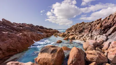 Turquoise rock pool surrounded by granite formations at Injidup Natural Spa, Western Australia.