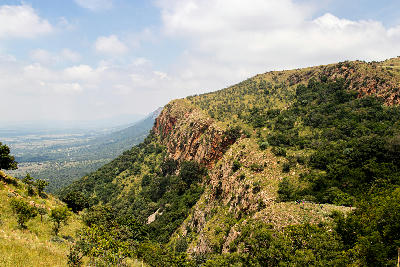 Hikers standing on a ridge above steep cliffs and valleys in the Magaliesberg mountains, South Africa.