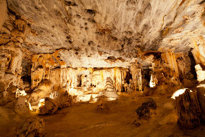 Large illuminated limestone cave chamber with stalactites and flowstone formations inside the Cango Caves near Oudtshoorn in South Africa.