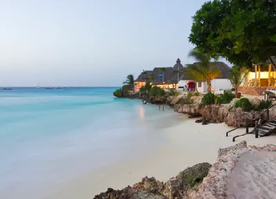 Calm evening light over the white sand and coral shoreline at Nungwi Beach with beachfront lodges overlooking the Indian Ocean, Zanzibar, Tanzania.