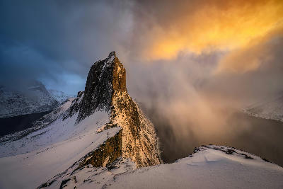 Snow-covered Segla mountain with steep ridge above fjords at sunset on Senja Island