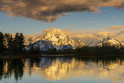 Mount Moran reflected in calm water at Oxbow Bend with golden light on the mountain, Grand Teton National Park, Wyoming.