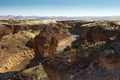 Panoramic view of Sesriem Canyon with rocky cliffs and winding river basin in the Namib Desert of Namibia.