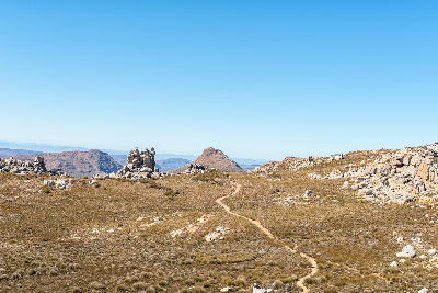 The Bokveldskloof hiking trail winding through open sandstone wilderness near the Maltese Cross in the Cederberg Mountains, with rocky outcrops and distant peaks on the horizon.