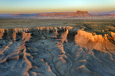 Aerial landscape of Southern Utah showing Factory Butte and layered desert badlands at sunrise.