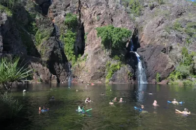 Visitors swimming and floating in the natural plunge pool beneath two waterfalls at Wangi Falls in Litchfield National Park, Northern Territory, Australia.