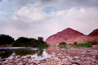 Orange River flowing through the Richtersveld with rocky riverbanks, desert mountains and riverside vegetation along the South Africa–Namibia border.