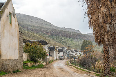 Historic cottages and dirt road in Wupperthal village beneath the rugged sandstone slopes of the Cederberg Mountains in South Africa's Western Cape.