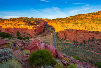 Burr Trail winds between towering red sandstone walls of Long Canyon illuminated by warm evening light.