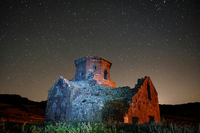 Red Church (Kızıl Kilise) in Cappadocia under a clear night sky, with stars visible above the stone structure in the Nevşehir region of Turkey.