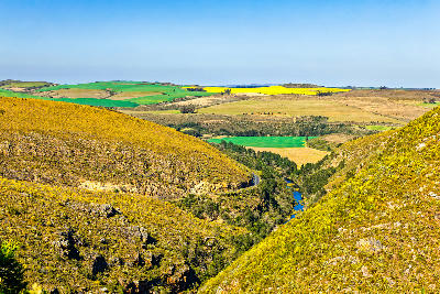 Tradouw Pass cutting through rugged hills toward patchwork farmland and coastal plains near Barrydale and Swellendam in the Western Cape, South Africa.