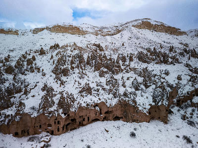 Aerial view of the snow-covered cave dwellings and rock-cut monastery at Zelve Open Air Museum in Cappadocia, Turkey.