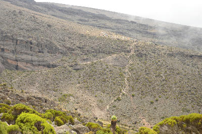 Hiking trail between Barranco Camp and Karanga Camp on Mount Kilimanjaro, with climbers crossing volcanic slopes below the Barranco Wall in Tanzania.