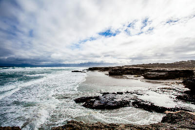 Storm clouds and breaking surf along the rocky shoreline of Walker Bay on the Hermanus coast in South Africa
