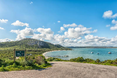 Road descending to Kraalbaai Beach on Langebaan Lagoon with houseboats and a jetty in West Coast National Park, South Africa.