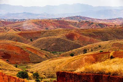 Eroded red laterite hills and layered valleys in the central highlands of Madagascar near Befato with dry grassland and rolling terrain patterns