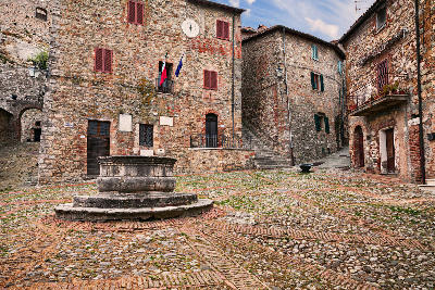 Piazza del Vecchietta in Castiglione d’Orcia, featuring a 16th-century stone well and the historic city hall in the Val d’Orcia, Tuscany, Italy.