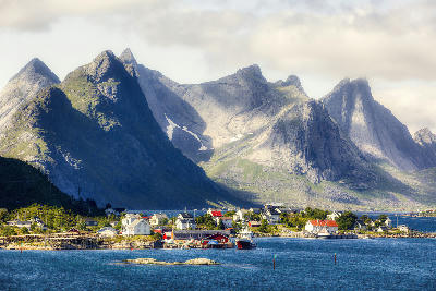 Fishing boats and houses in Reine with steep granite peaks rising above Reinefjorden in the Lofoten Islands, Norway.