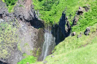 Furepe Waterfall seen from land, where thin streams spread across the basalt cliff face along the Shiretoko Peninsula.