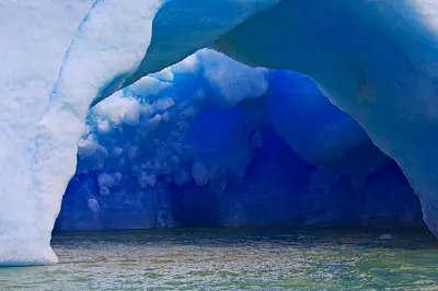 Blue iceberg arch grotto floating on Lago Argentino near Upsala Glacier in Patagonia, Argentina.