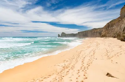 Wide view of Gibson Steps Beach with limestone cliffs, sea stacks and visitors on the Great Ocean Road, Victoria, Australia.