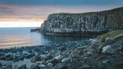 Rocky shoreline and towering, weathered coastal cliffs at Embleton Bay in Northumberland, England, beneath a softly coloured evening sky.