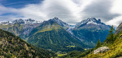 Panoramic view of Chamonix Valley showing forested slopes, central ridge, and glaciated peaks in the Mont Blanc massif.