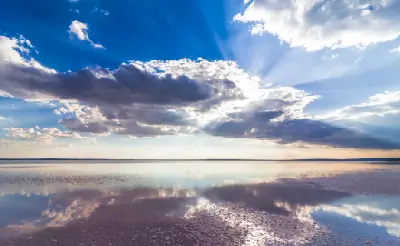 Sun rays breaking through dramatic clouds reflected in the shallow waters and salt flats of Lake Tuz, Turkey.