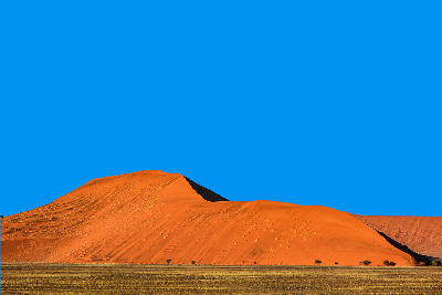 Minimal desert landscape of Dune 45 in Namibia with orange sand dunes beneath a clear blue sky.