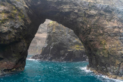 Boat-level view beneath a basalt sea arch along the Vestmanna bird cliffs, Streymoy, Faroe Islands.