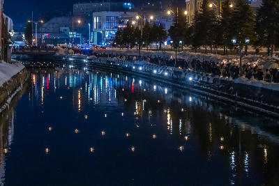 Snow-covered canal with floating candle lights and night reflections along Otaru Canal in Hokkaido, Japan.