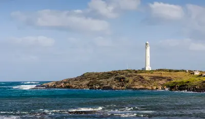 Cape Leeuwin Lighthouse rises above a rocky headland surrounded by the ocean.