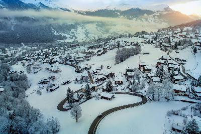 Aerial winter view of Grindelwald village and valley with snow-covered fields and roads, Switzerland.