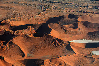 Aerial view of red sand dunes and white clay pans in the Namib Desert of Namibia.