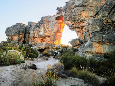 Sunlight illuminating Wolfberg Arch in the Cederberg Wilderness, with warm golden light glowing through the sandstone opening, Western Cape, South Africa.