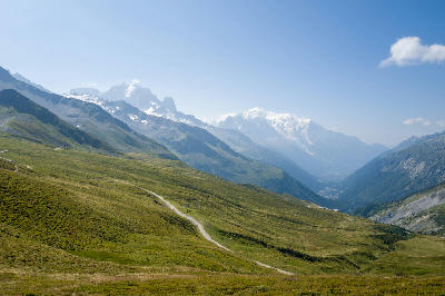 Panoramic view of Chamonix Valley with Mont Blanc massif in the background and green alpine slopes in the foreground.