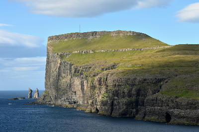 Risin og Kellingin sea stacks rising offshore from Tjørnuvík with high basalt cliffs of Streymoy in the foreground, Faroe Islands.