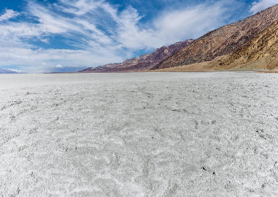 Expansive salt flats of Badwater Basin — vast evaporated basin below sea level with subtle salt crust textures and mountain backdrops.