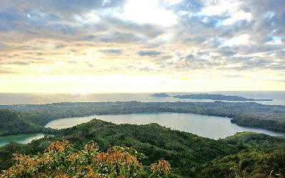 Sunset landscape from Nosy Be in Madagascar showing volcanic crater lakes, tropical hills, and the Indian Ocean horizon.