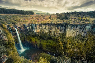 Wide view of Mac Mac Falls dropping into a deep canyon surrounded by towering cliffs and escarpment vegetation in Mpumalanga, South Africa.