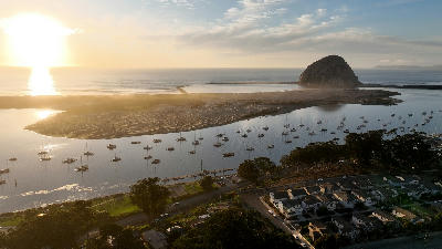 Morro Bay harbor with boats and Morro Rock at sunset California