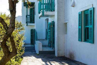 Whitewashed resort buildings with turquoise shutters and balconies at Club Mykonos in Langebaan, featuring architecture inspired by the Greek island of Mykonos.
